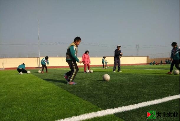 學(xué)生在人造草足球場(chǎng)上踢球